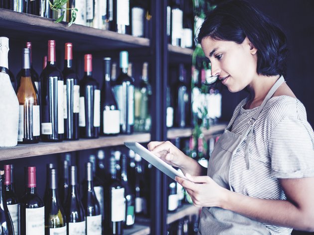 Frau steht vor Weinregal im Supermarkt